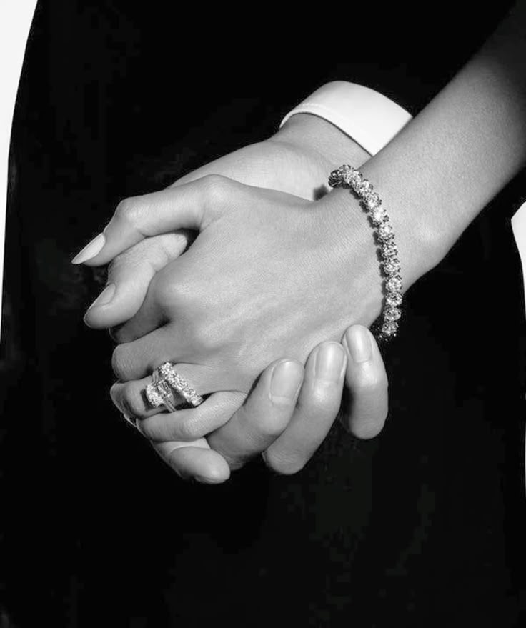 A person resting their hands on denim while wearing stacked rings and a watch