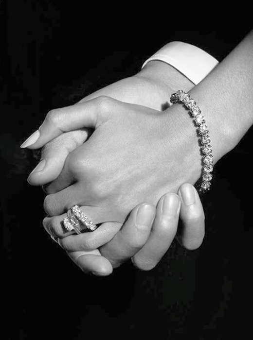 A person resting their hands on denim while wearing stacked rings and a watch